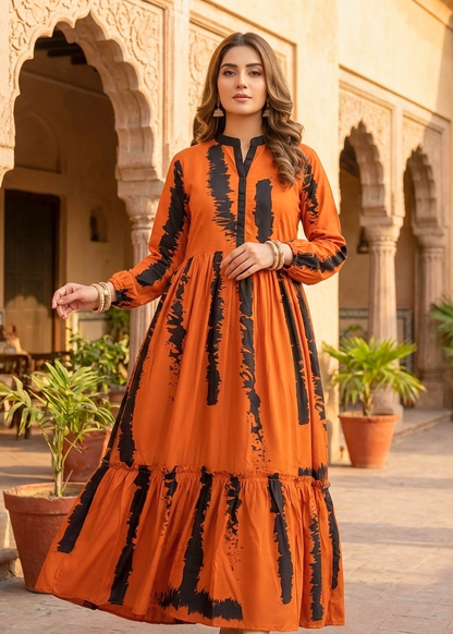 Woman in an orange dress with black patterns standing in a sunlit courtyard.