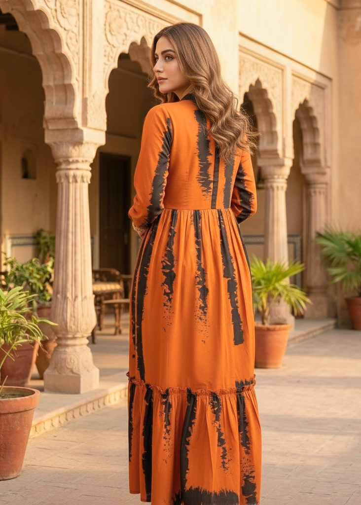 Woman in an orange and black dress standing in a courtyard with architectural columns and potted plants.